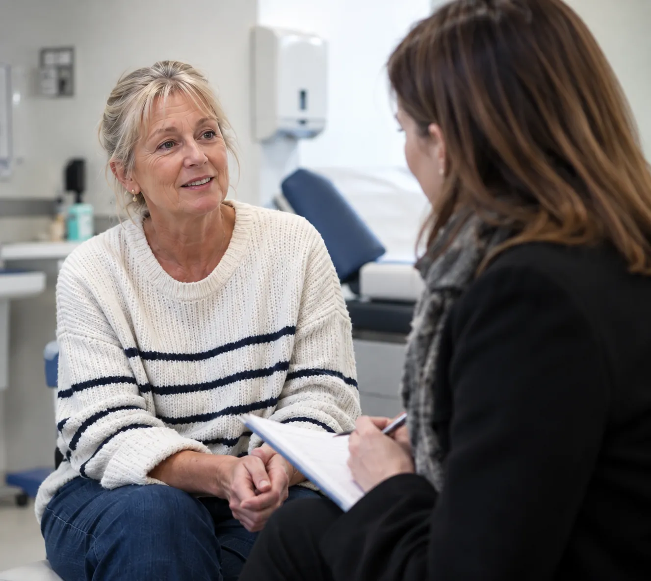 A healthcare consultant taking notes while talking with a patient in a clinic consulting room